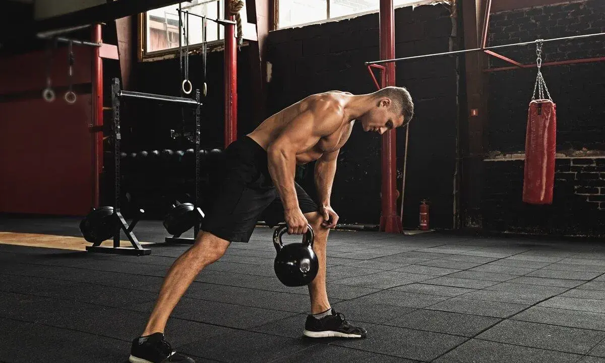 Mężczyzna wykonuje trening funkcjonalny ćwiczenia z kettlebell w siłowni.