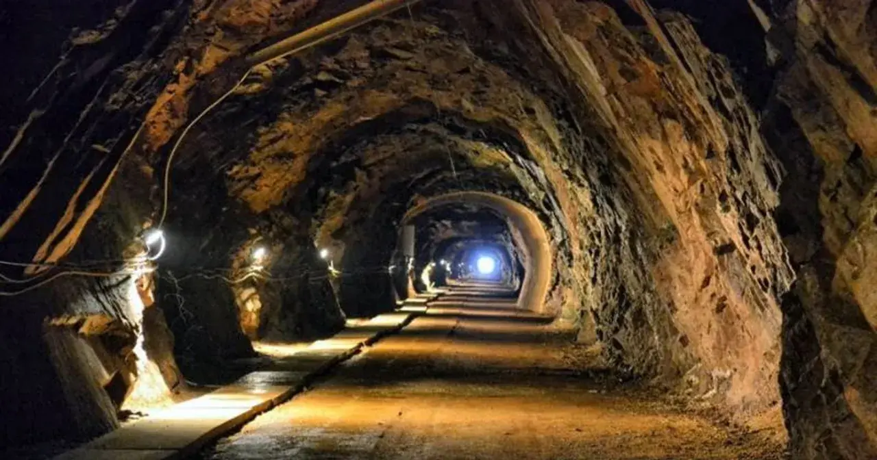 Wąski tunel w kopalni, oświetlony lampami, prowadzi w głąb ziemi. To jedne z wielu tajemniczych jaskiń Dolnego Śląska.
