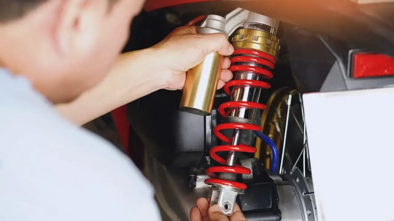 Mechanik wymienia amortyzator w skuterze. Sprawdź wymiana amortyzatorów cena i dowiedz się, ile kosztuje serwis.