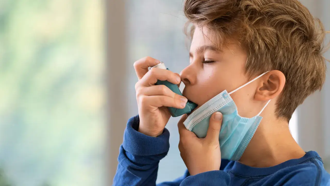 Junge mit Inhalator und Maske. Gute Behandlung beeinflusst die asthma lebenserwartung positiv.