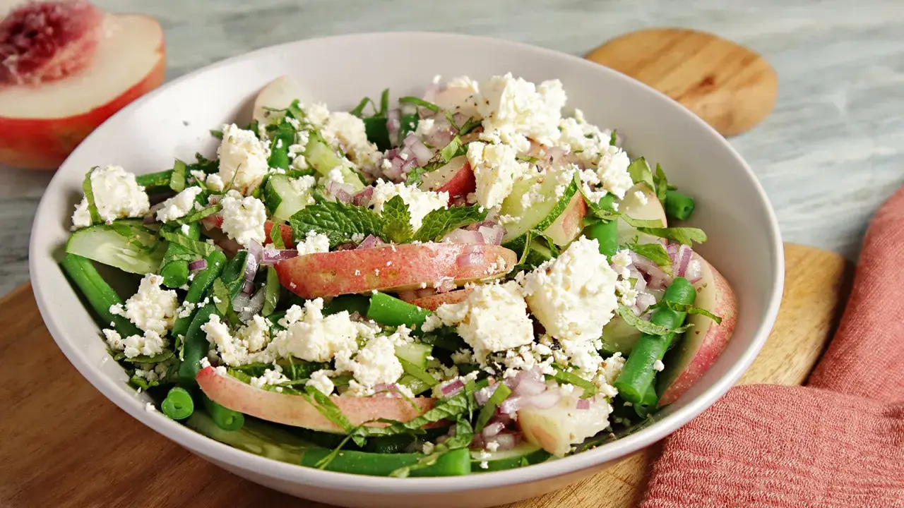 Erfrischender Salat mit Nektarinenstücken, grünen Bohnen, Gurke, roten Zwiebeln und zerbröseltem Feta.