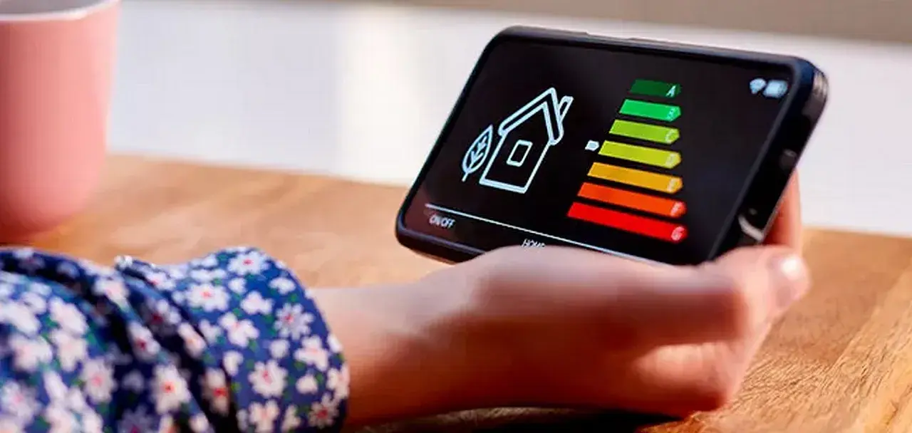 Écran de smartphone affichant une maison et un barème d'efficacité énergétique. La question "une clim consomme plus en chaud ou froid" est implicite.
