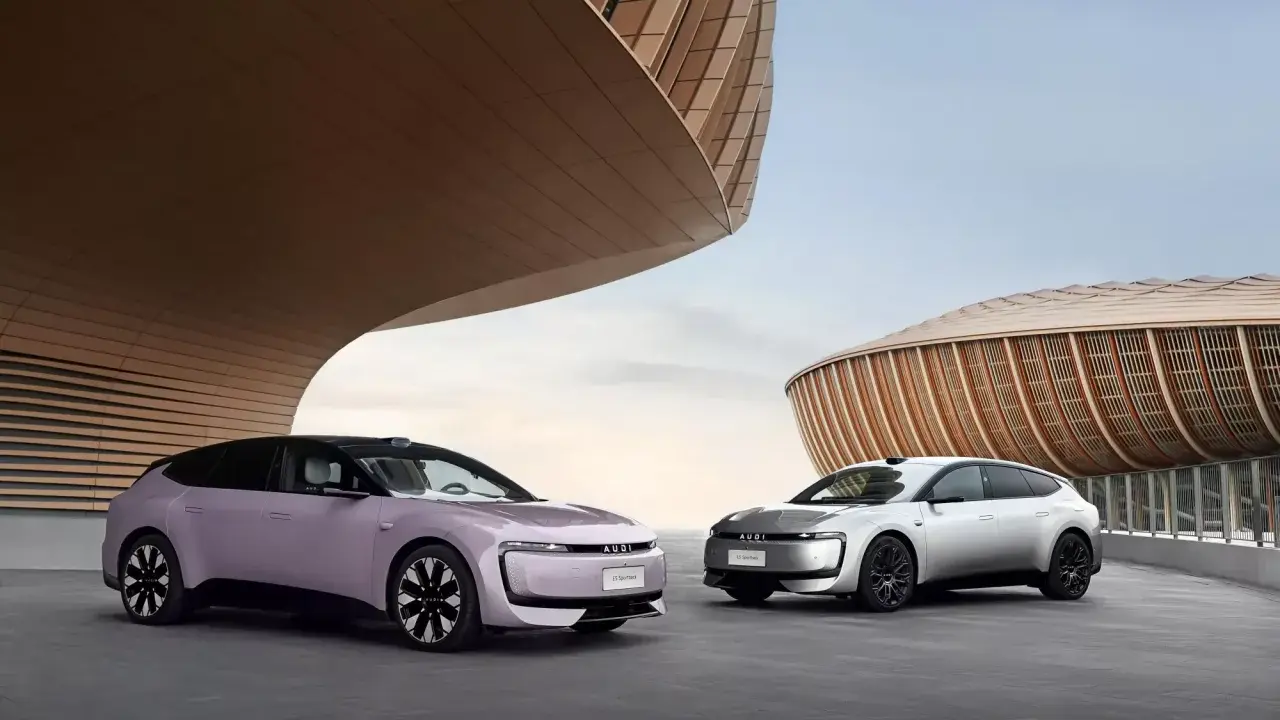 Deux Audi E5 Sportback, une lilas et une argentée, se présentent devant des bâtiments aux formes organiques.