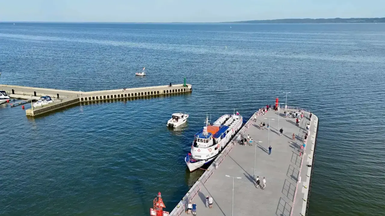 Ludzie czekają na rejsy z Krynicy Morskiej. Statek "Anita" zacumowany przy molo, obok mniejsze łodzie.
