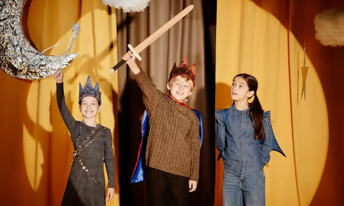 Niños en un escenario, listos para obras de teatro para niños. Uno sostiene una espada, otro una luna y una varita mágica.