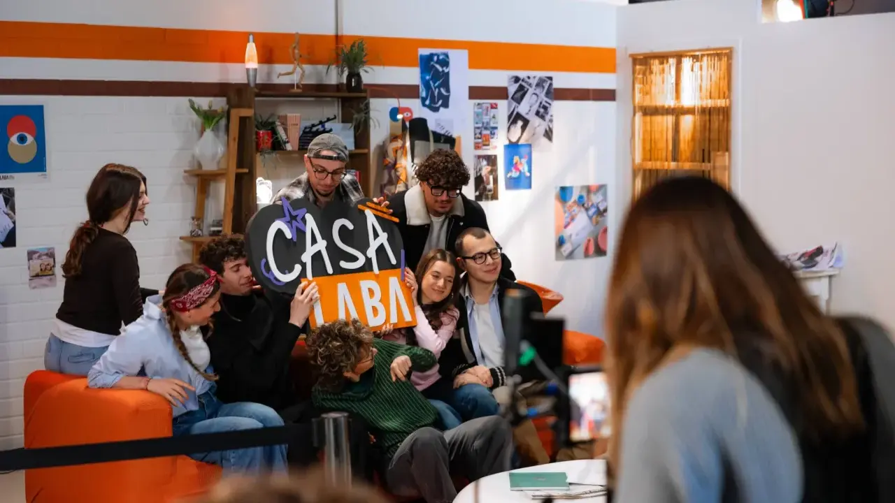 A group of young people pose for a photo, holding a sign that says "CASA LABA".