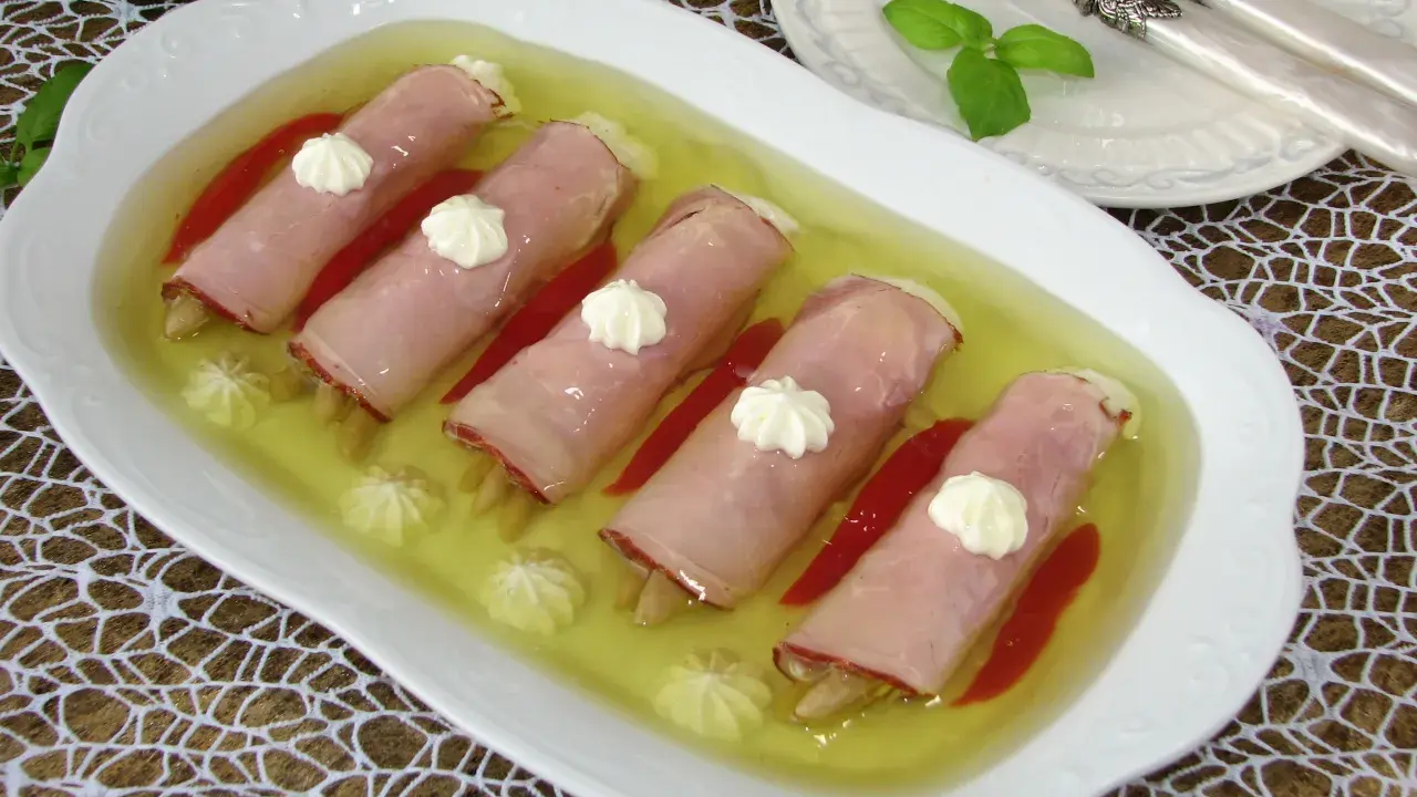 Roladki z szynki z papryką w galarecie, ozdobione kleksami majonezu. Elegancka przystawka na specjalne okazje.