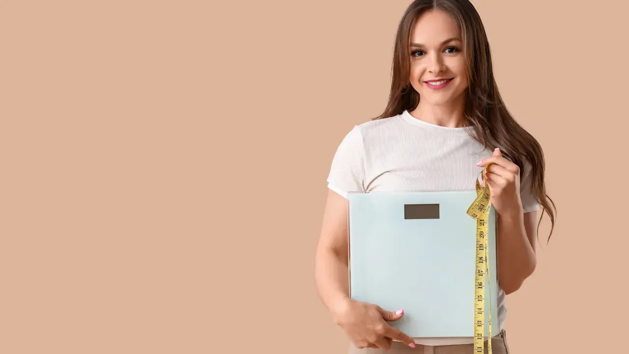 Femme souriante tenant une balance et un mètre ruban, prête à perdre 10 kilos.