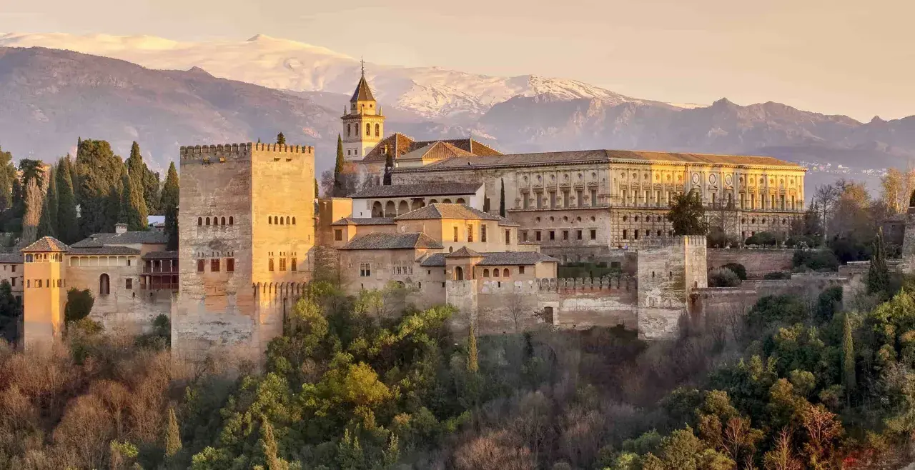 Die Alhambra in Granada, ein Traumziel nach einer Reise von Sevilla. Majestätische Festungsmauern und Paläste vor schneebedeckten Bergen.