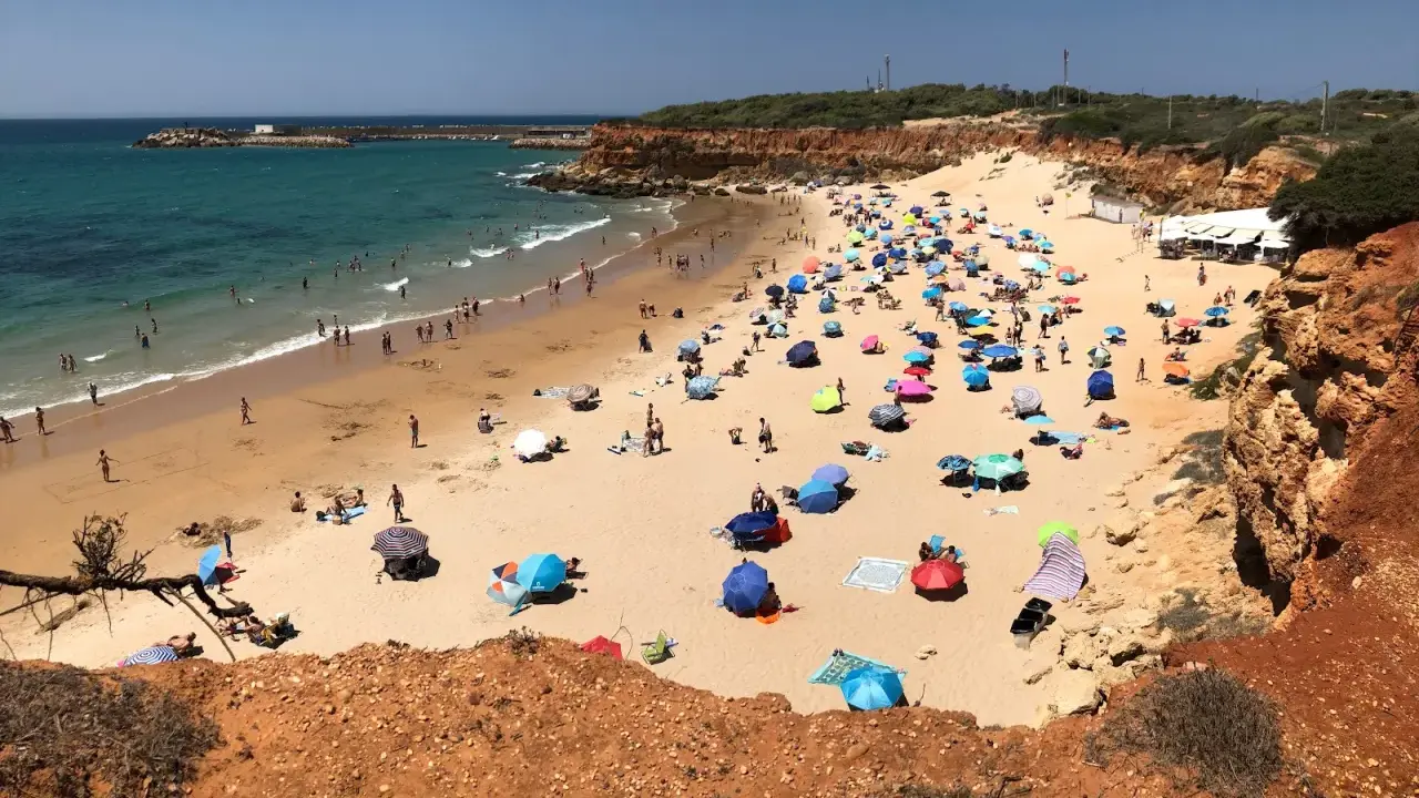 Sonniger Tag am playa fuente del gallo mit vielen bunten Sonnenschirmen und Badegästen im türkisfarbenen Meer.