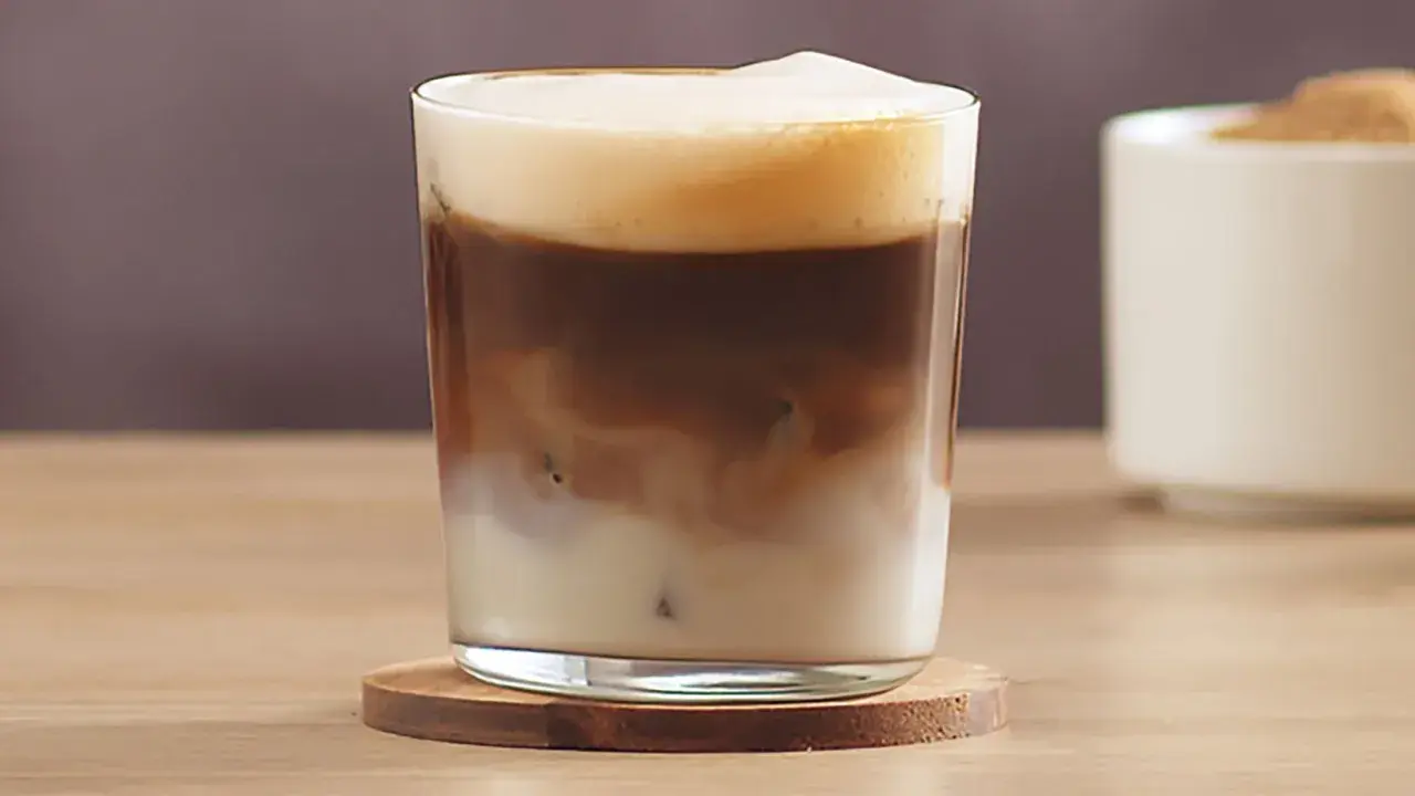 Ein erfrischender kalter Latte Macchiato mit cremiger Schaumkrone und Eiswürfeln.