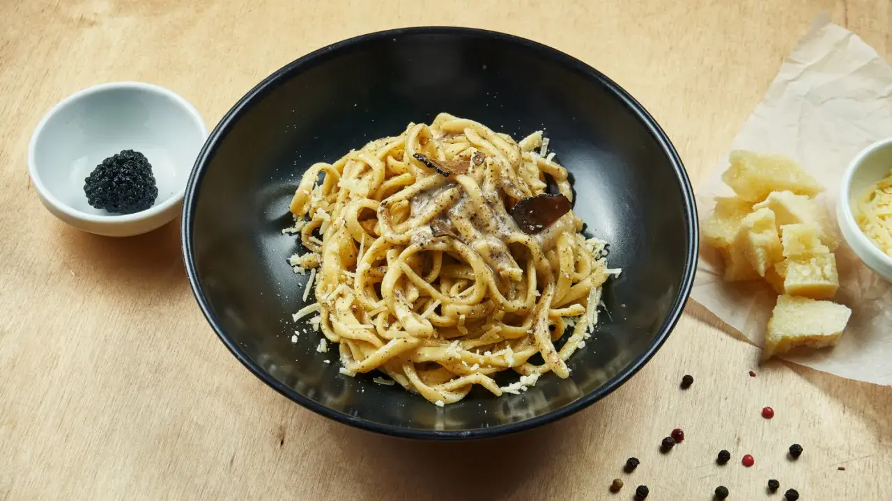 Un piatto di pasta al tartufo, un sapore autentico del cibo perugino, con scaglie di parmigiano e pepe nero.