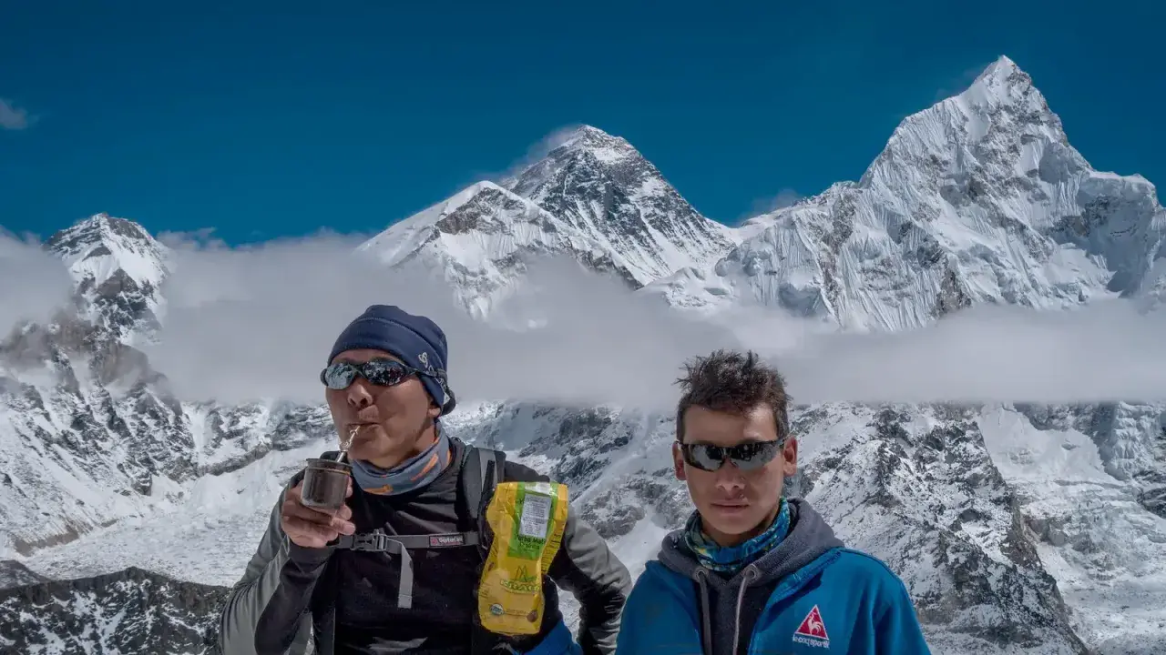 Niesamowity widok z Mount Everest. Dwóch wspinaczy odpoczywa, jeden pije yerba mate, podziwiając majestatyczne szczyty.