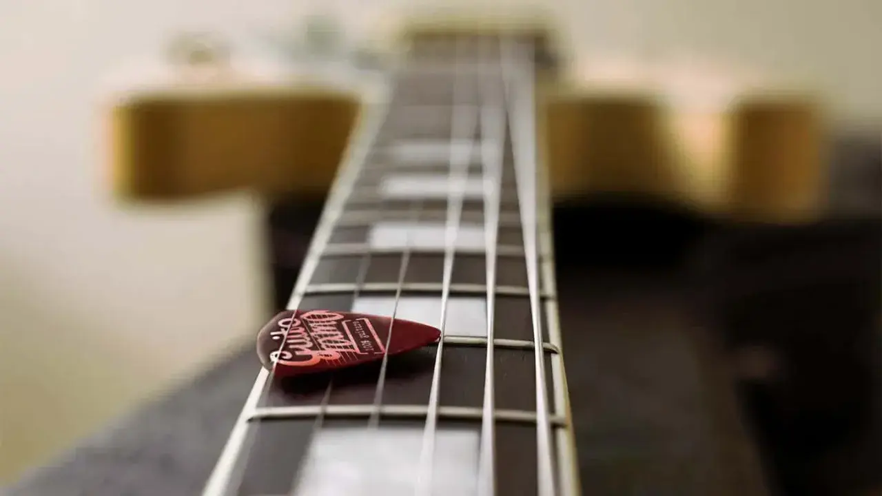 Médiator sur le manche d'une guitare, prêt à jouer une gamme arabe.