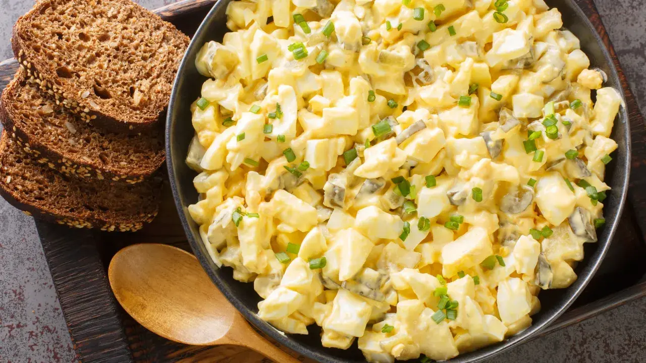 Cremiger Eiersalat mit Gurkenstückchen und Schnittlauch, garniert, serviert mit Vollkornbrot. Ein einfaches eiersalat rezept.