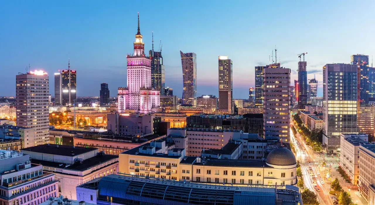 Warszawski krajobraz miejski nocą, z Pałacem Kultury i Nauki w centrum. Wiele nowoczesnych budynków, gdzie znajdują się uczelnie prywatne Warszawa.