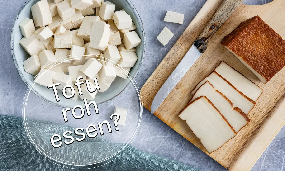 Würfel und Scheiben von Tofu liegen neben einem Messer auf einem Holzbrett. Die Frage "Kann man Tofu roh essen?" wird gestellt.