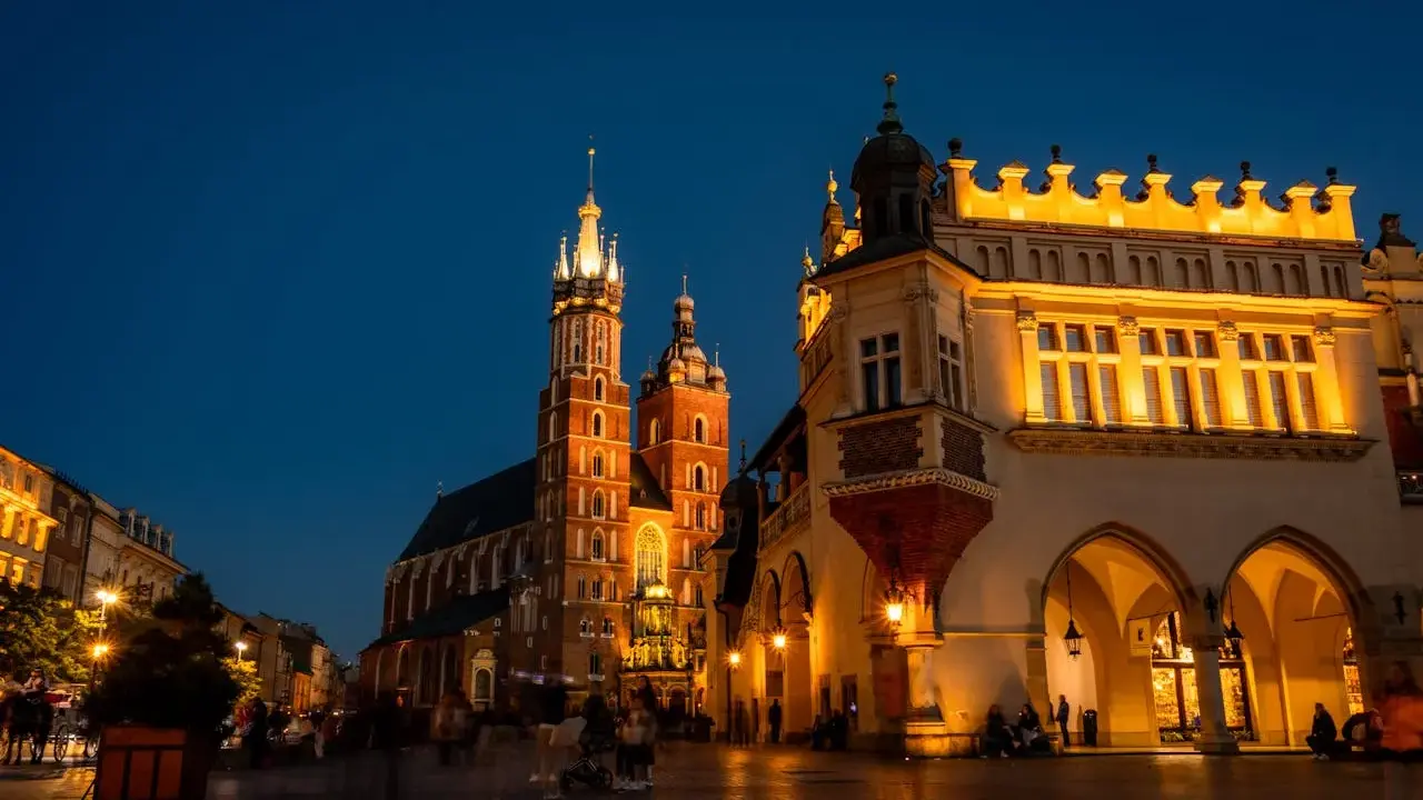 Wieczorny spacer po Rynku Głównym w Krakowie. Sukiennice i Kościół Mariacki oświetlone, tworzą magiczną atmosferę na udany weekend w Krakowie.