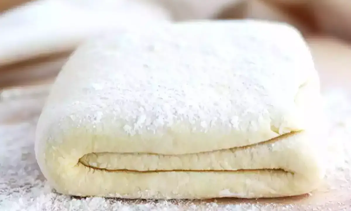 Pâte feuilletée prête à être utilisée pour votre recette. Les couches sont bien visibles, saupoudrées de farine.