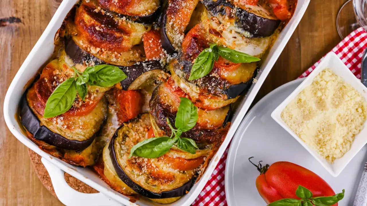 Gebackene Auberginen-Tomaten-Schichten in Auflaufform, garniert mit Basilikum. Perfekt, um Auberginen haltbar zu machen und köstlich zu genießen.