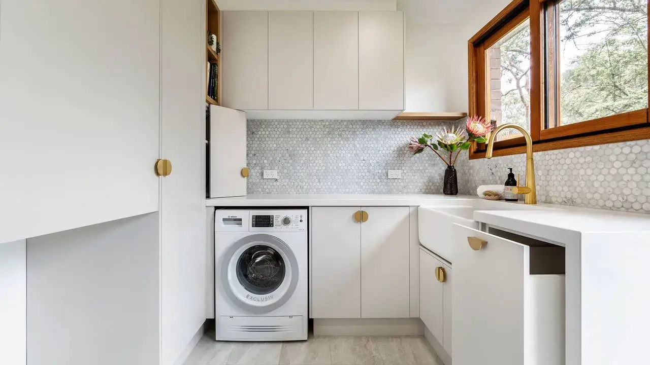 Lavanderia piccola moderna con lavatrice, lavello bianco, rubinetto dorato e finiture eleganti. Ottime idee per sfruttare ogni spazio.