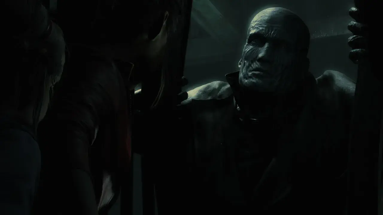 Potworna twarz Nemesisa z Resident Evil w mroku, groźnie spogląda na Claire.