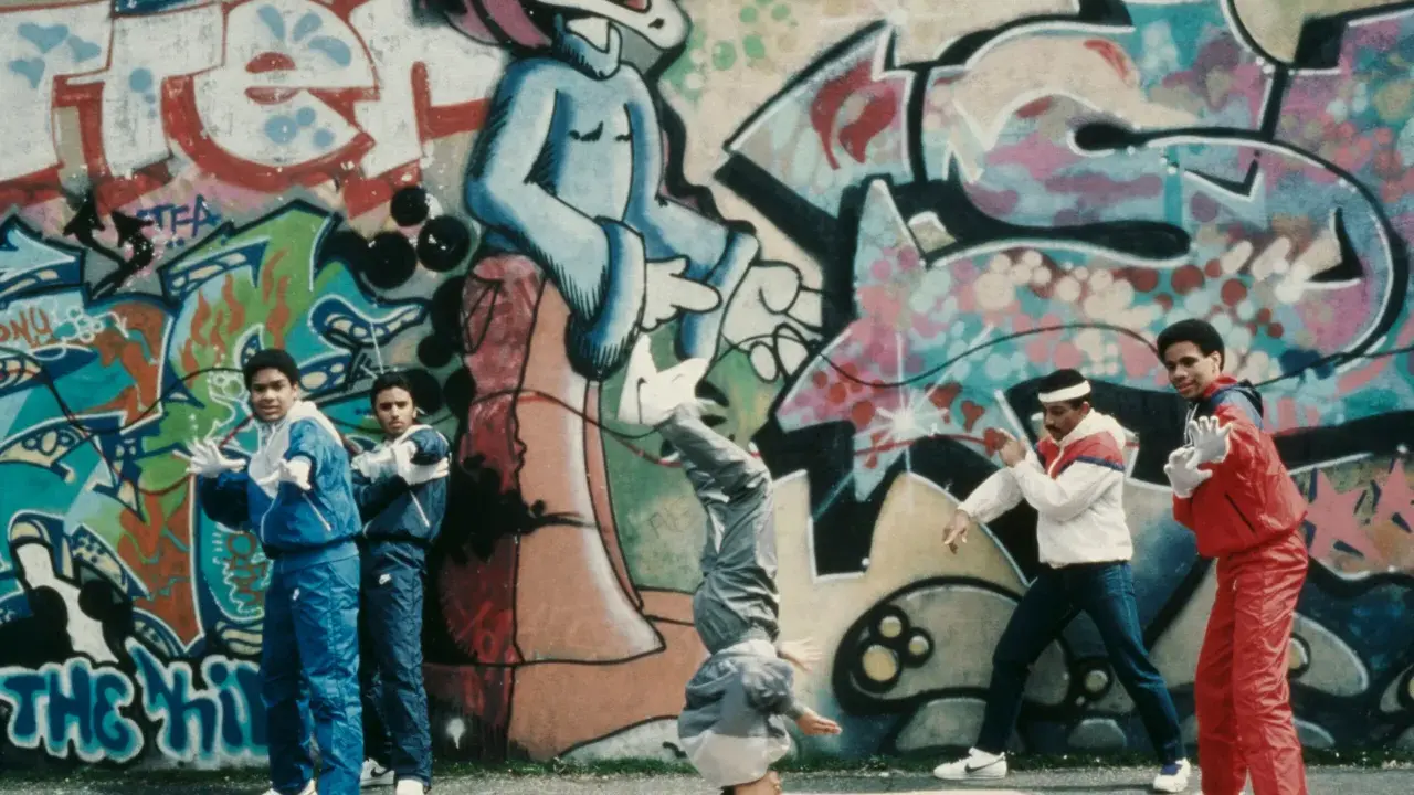 A group of young people showcase their moves in front of vibrant graffiti art, embodying the spirit of hip hop culture art.
