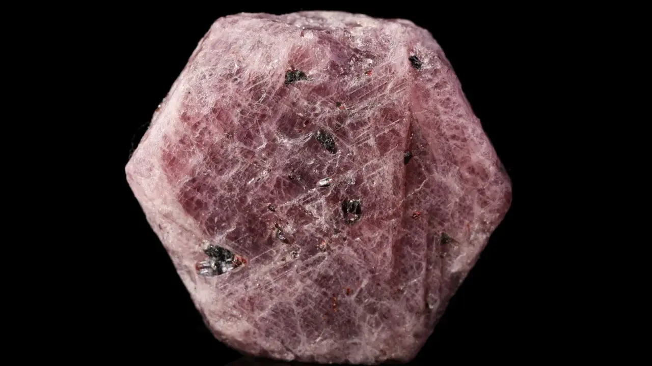 Cristallo grezzo di corindone rosa, con inclusioni scure. Il corindone, con il suo significato di forza e passione, si presenta in questa forma naturale.