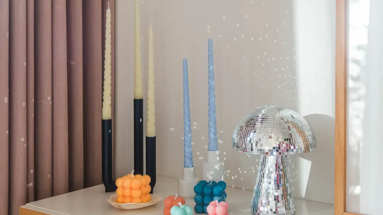 En samling av DIY ljus i olika former och färger, inklusive bubbel- och vridna ljus, samt en glittrig svampformad dekoration.