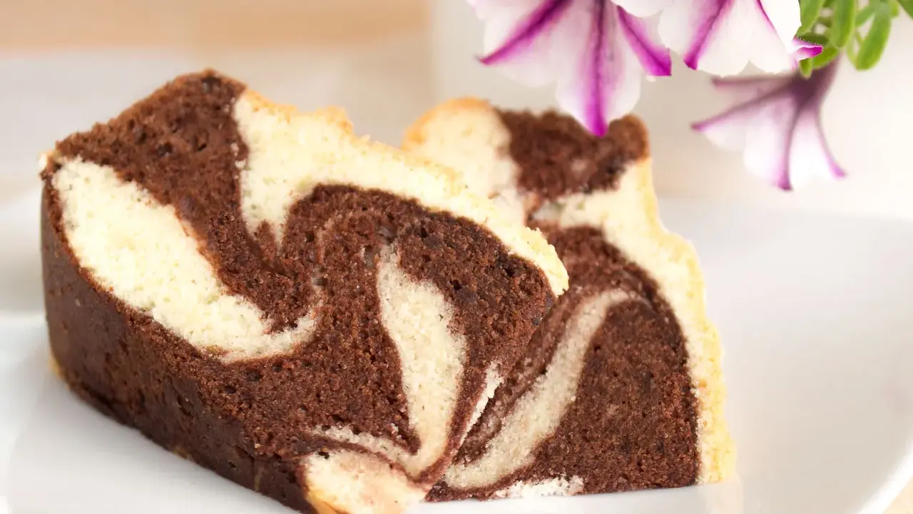 Zwei Stücke saftiger Marmorkuchen mit schöner Maserung, perfekt für ein gemütliches Kaffeetrinken. Dieses Marmorkuchen Rezept ist ein Klassiker.
