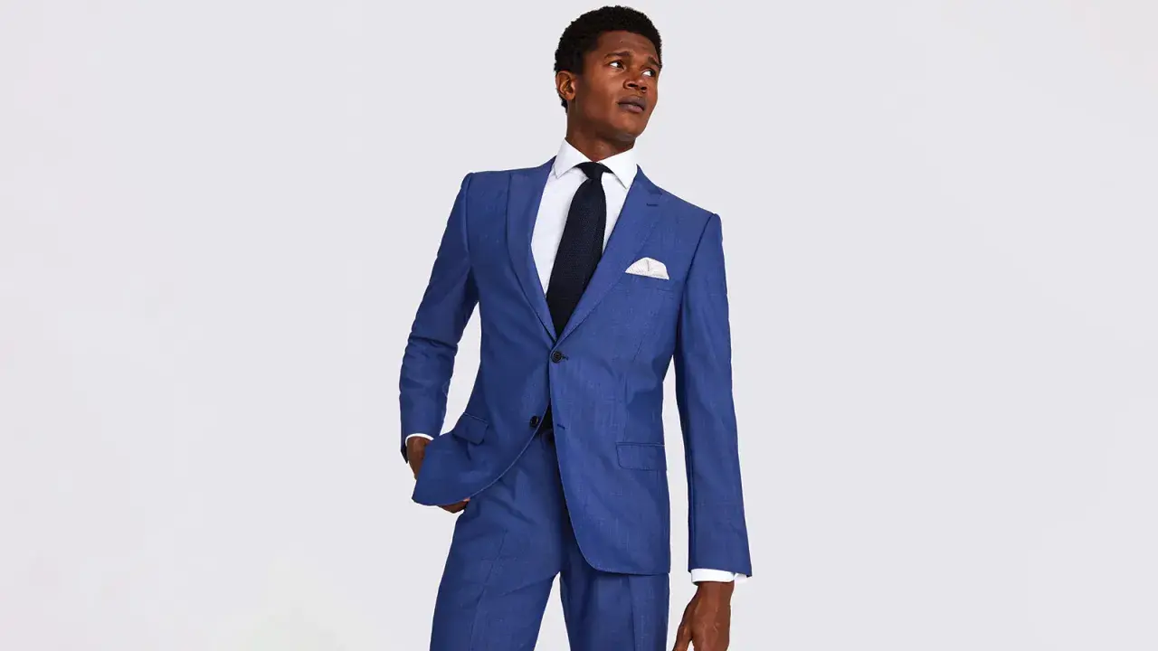 A man in a sharp blue suit, white shirt, and dark tie. This image helps answer how much should a suit cost.