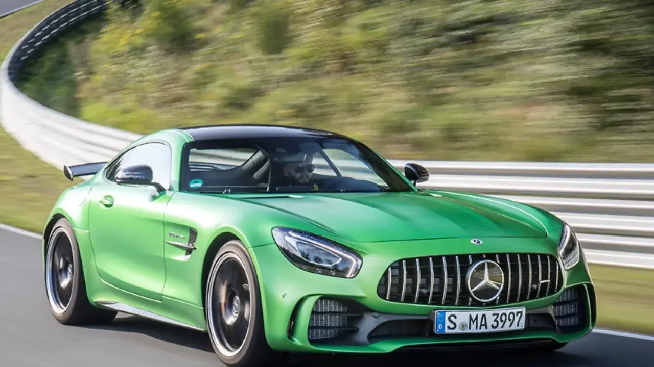 Grüner Mercedes-AMG GT R auf Rennstrecke, Fahrer im Fokus.