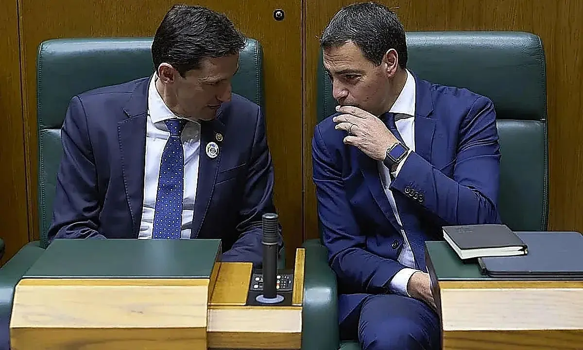 Dos hombres de traje azul conversan en un parlamento. Uno, con corbata de puntos, escucha atentamente. El otro, con la mano en la barbilla, parece reflexionar. ¿Qué debate se estará gestando?