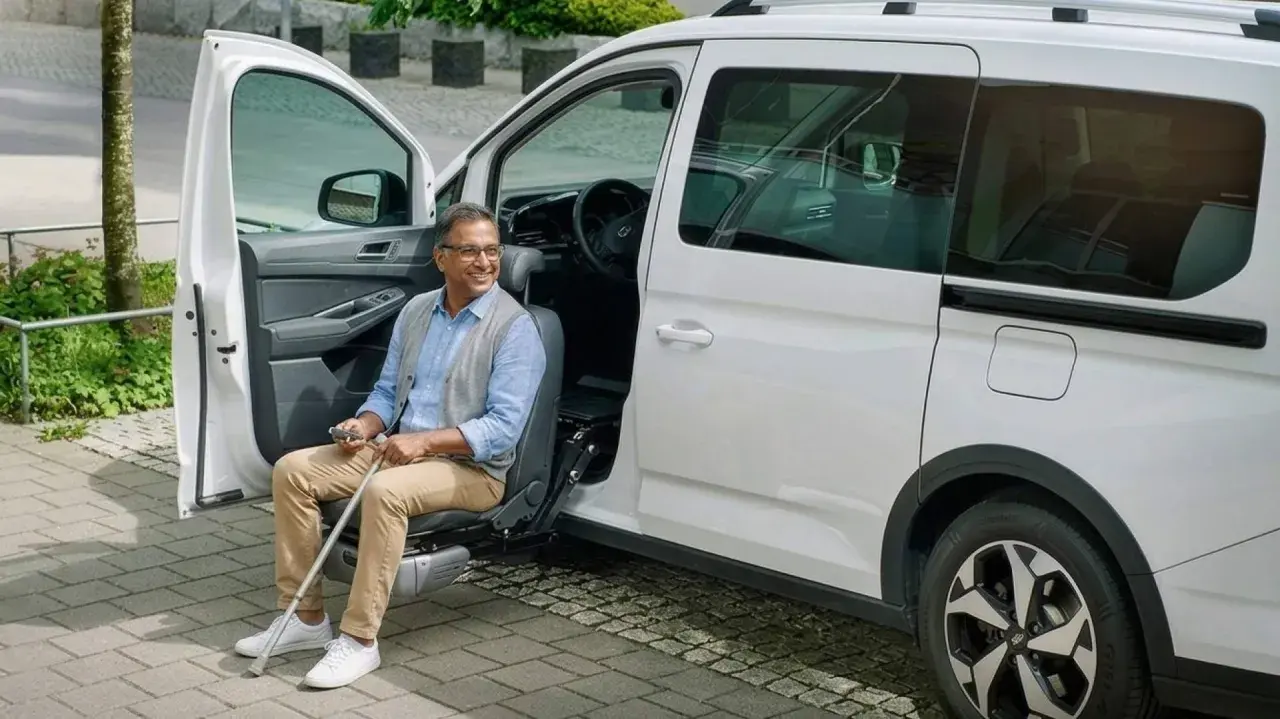 Hombre sonriente sentado en un asiento elevador de coche, listo para salir. Un ejemplo de soluciones de movilidad accesibles.