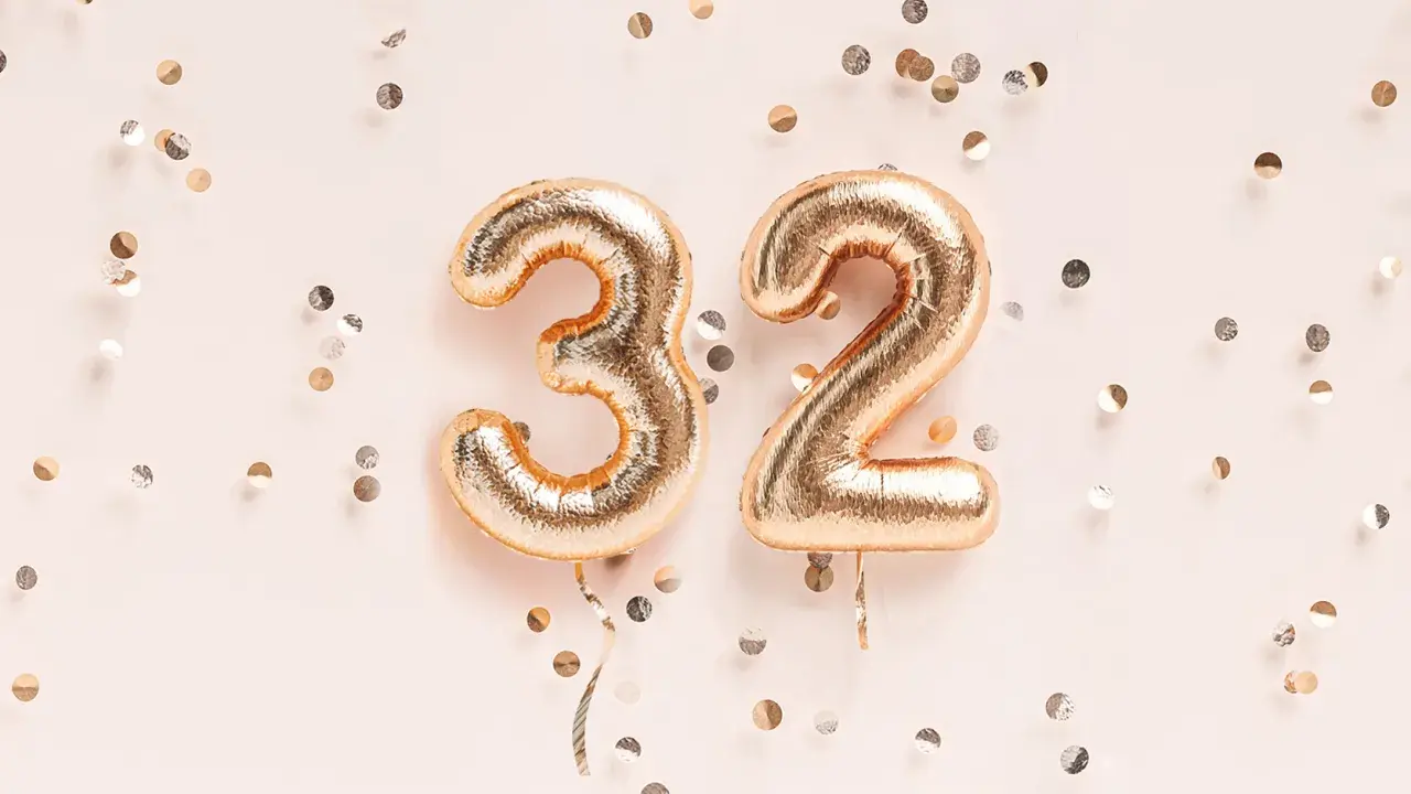 Złote balony z cyframi 3 i 2, otoczone konfetti. To już 32 tydzień ciąży, czas na świętowanie!