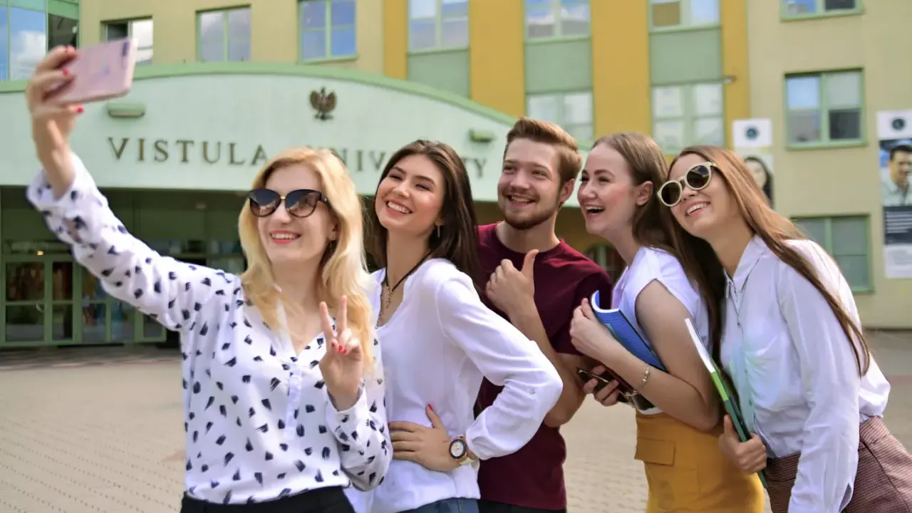 Studenci filologii angielskiej w Warszawie robią sobie selfie przed Uniwersytetem Vistula.