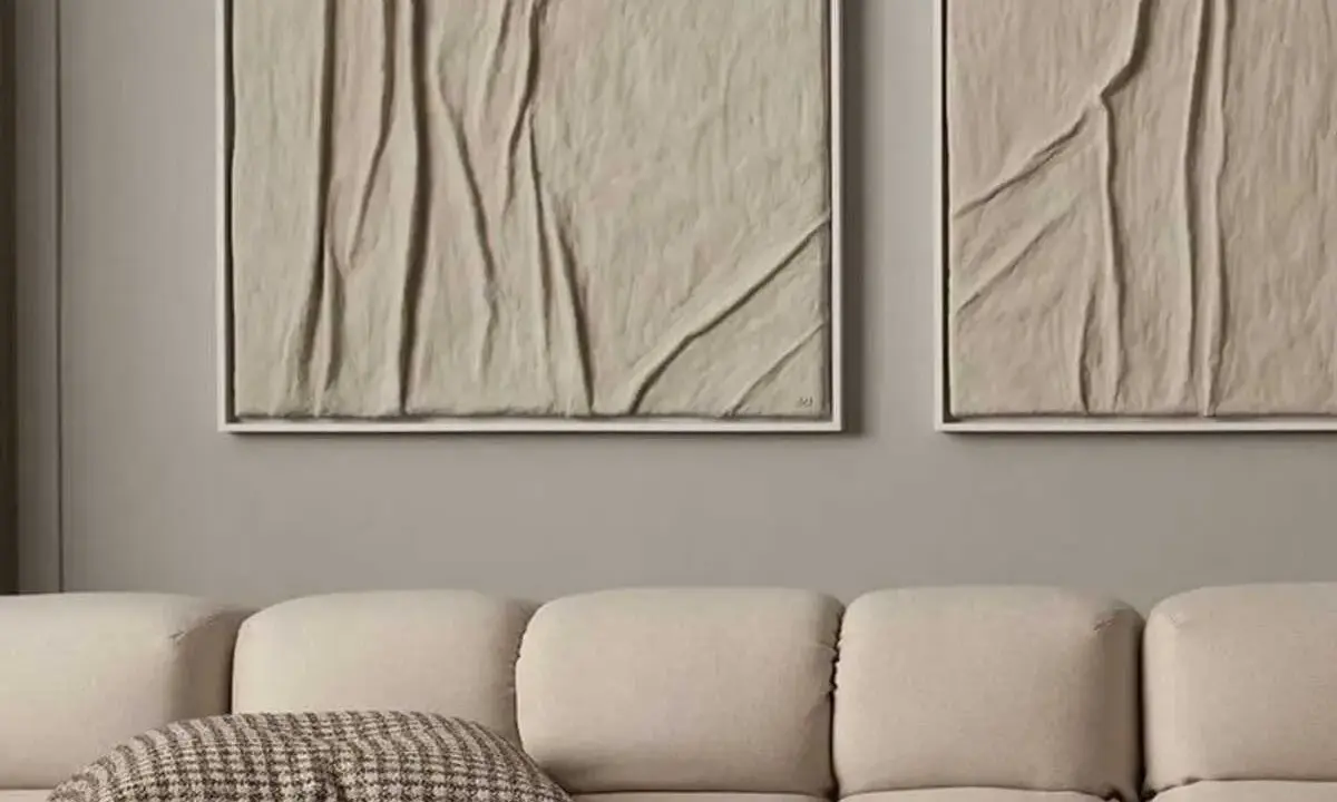 Deux tableaux texturés, style diy tableau relief, aux tons sable, accrochés au-dessus d'un canapé beige.