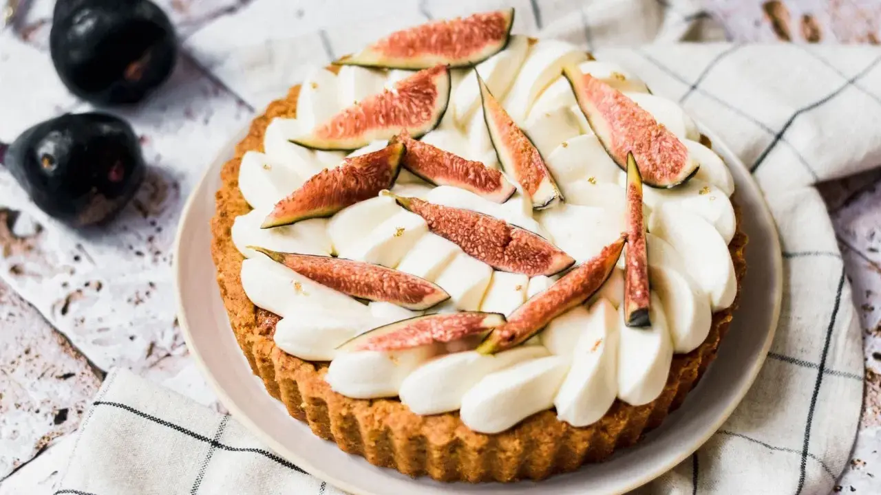 Tarte aux figues fraîches et crème fouettée, décorée de feuilles d'or.