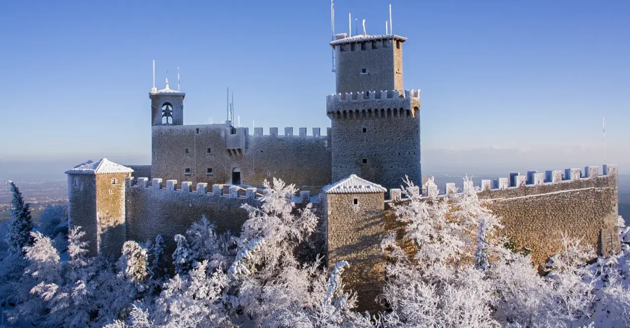 Le tre torri di San Marino innevate, un magico **percorso 3 torri San Marino** sotto un cielo azzurro.