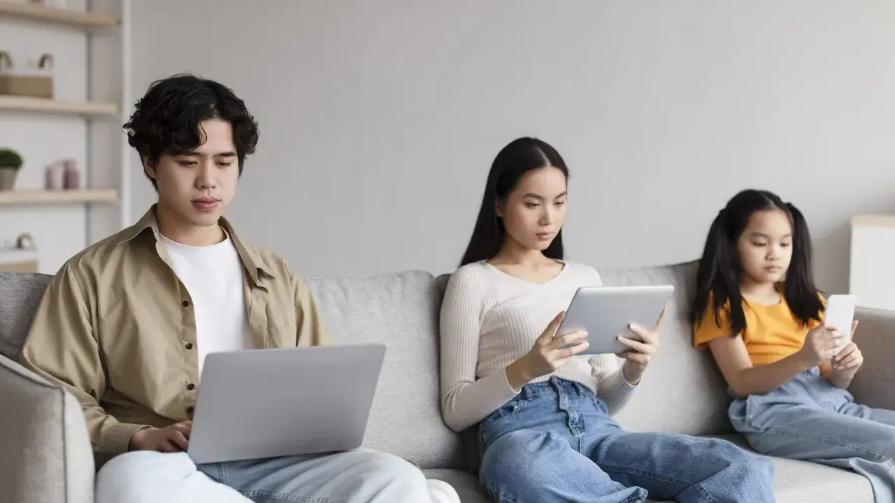 Trois personnes sur un canapé : un jeune homme sur un ordinateur portable, une femme sur une tablette, et une jeune fille sur un smartphone. Le temps d'écran recommandé pour 13 ans est dépassé pour certains.