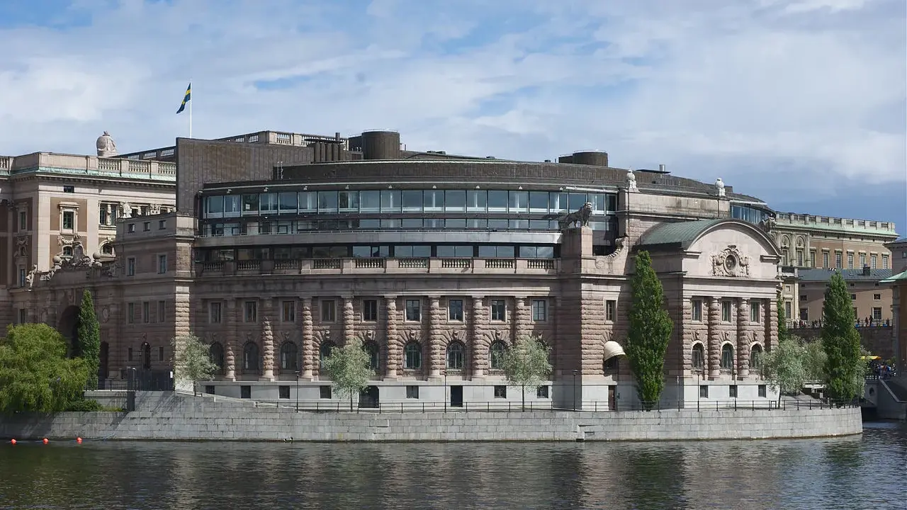 Riksdagshuset i Stockholm, en symbol för sveriges statsskick, med sin moderna glasdel och klassiska stenfasad vid vattnet.