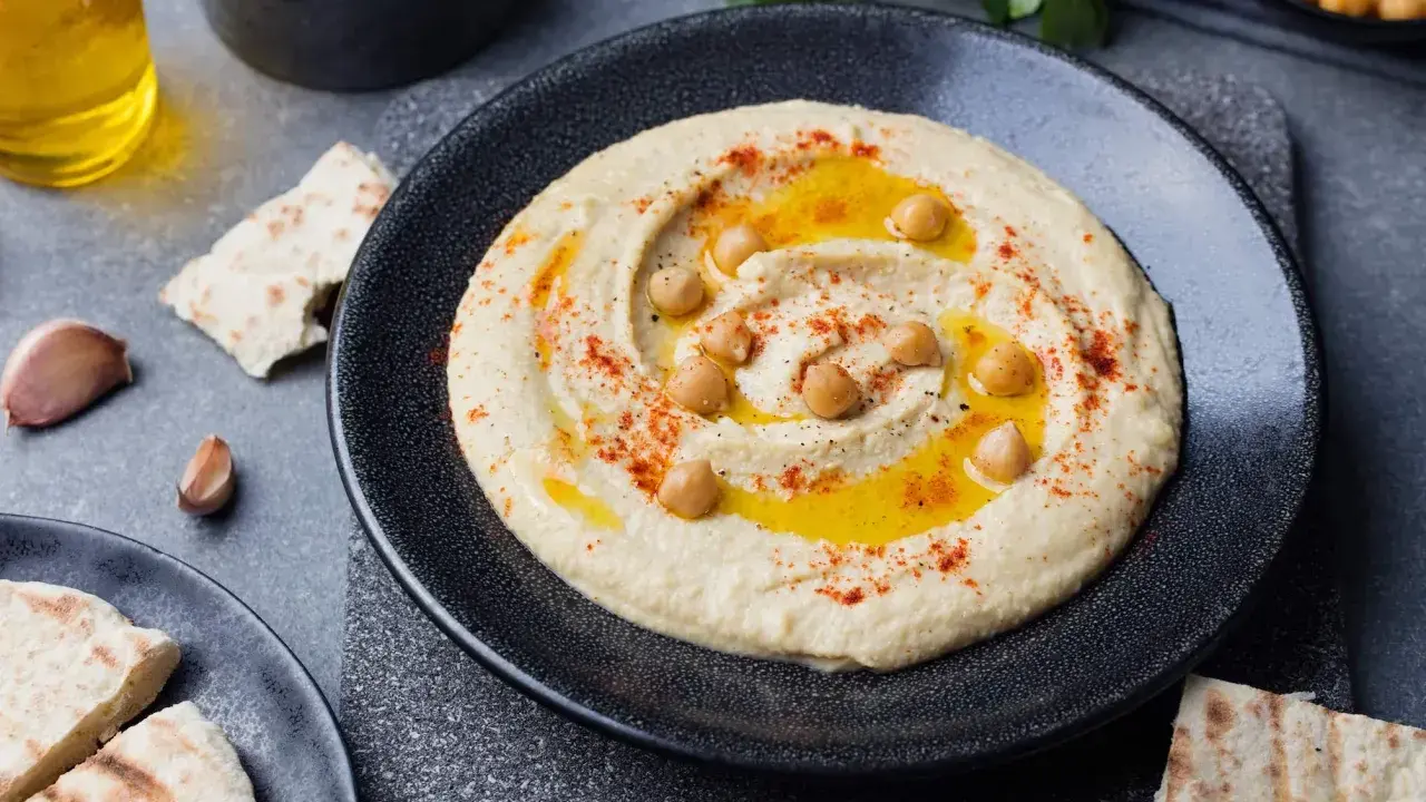 Pyszny, kremowy hummus co to jest? To pasta z ciecierzycy, oliwy, czosnku i przypraw, podana z pitą.