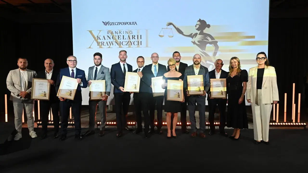 Grupa prawników odbiera nagrody na tle ekranu z logotypem "Rzeczpospolitej" i grafiką Temidy.