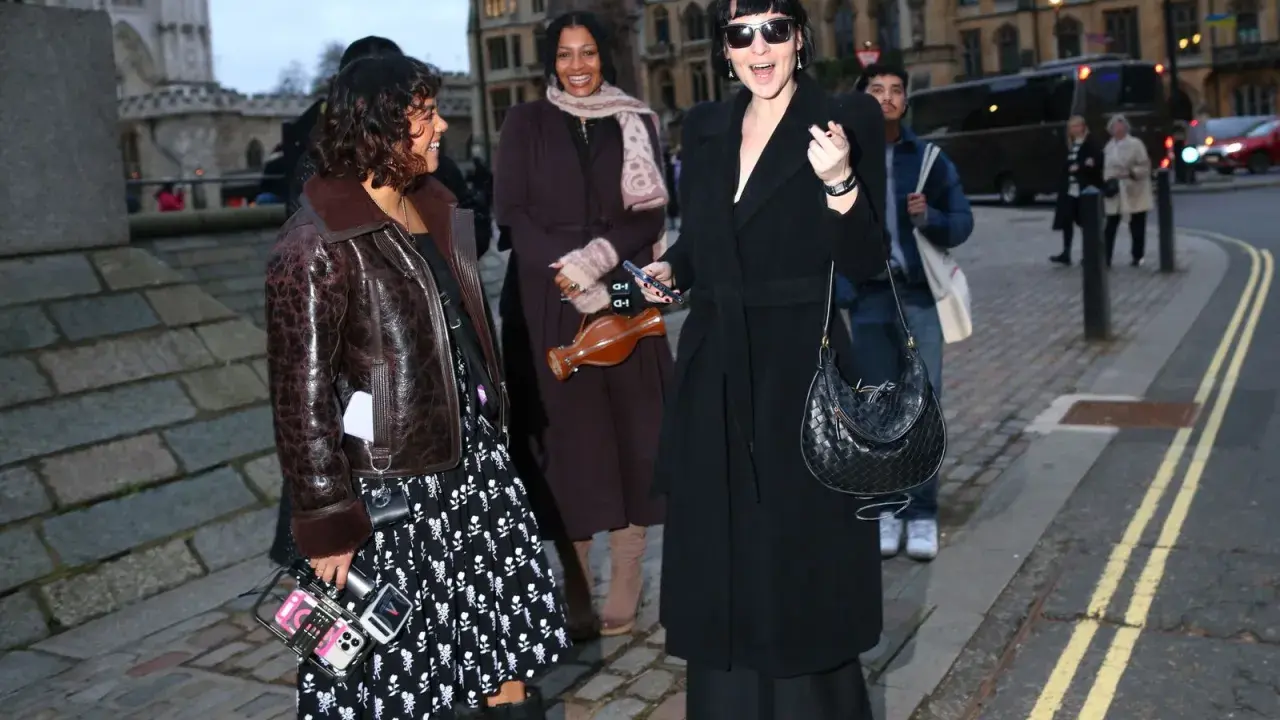 Un elegante cappotto a vestaglia nero, indossato con disinvoltura, si abbina perfettamente a un look audace e moderno.