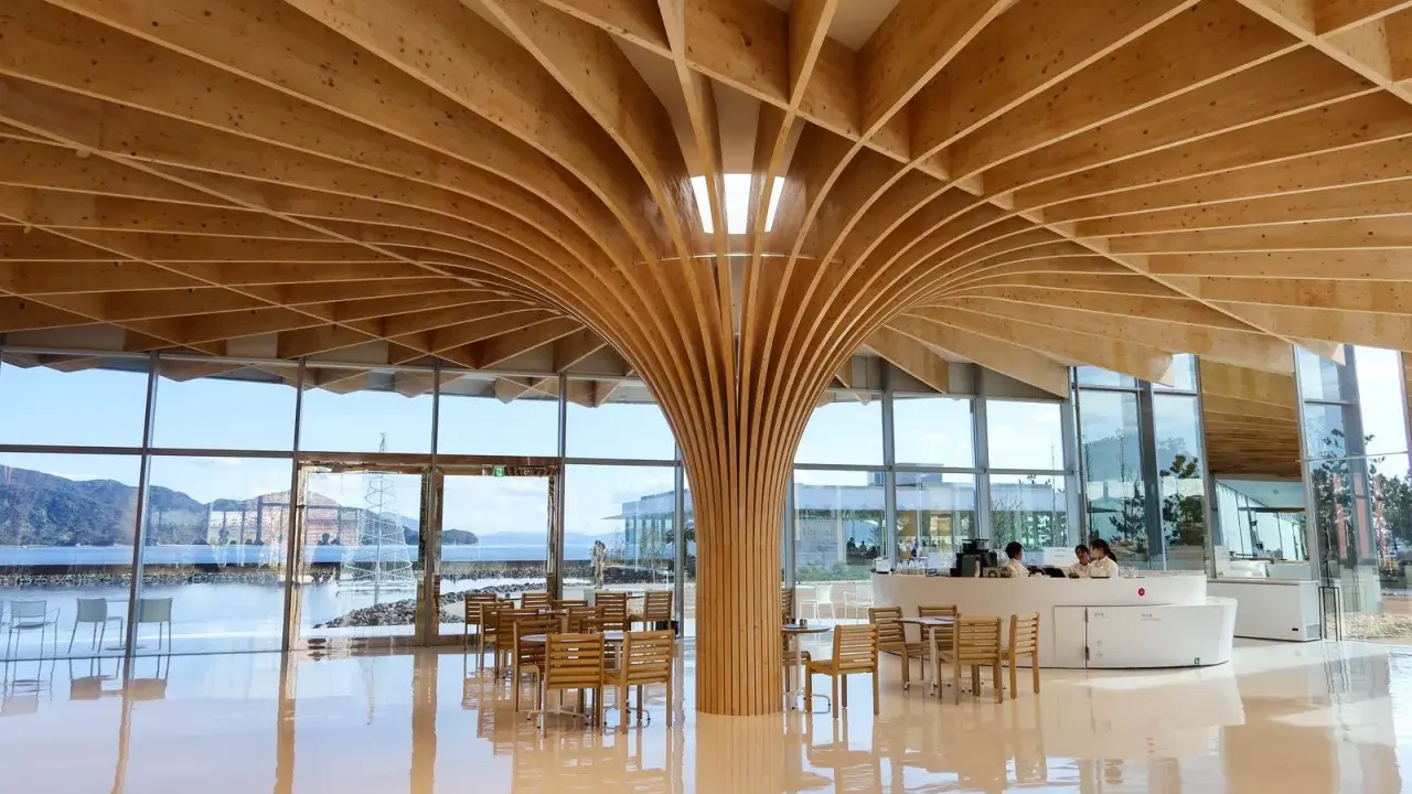 Interno moderno con soffitto in legno curvo, un esempio di architettura giapponese. Tavoli e sedie in legno, vista sul mare.