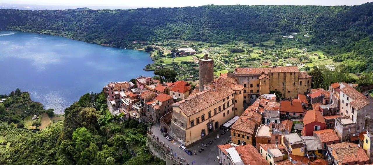 Nemi, un borgo incantevole a breve distanza da Roma, si affaccia sul lago. Case con tetti rossi si aggrappano alla collina, circondate da verde lussureggiante.