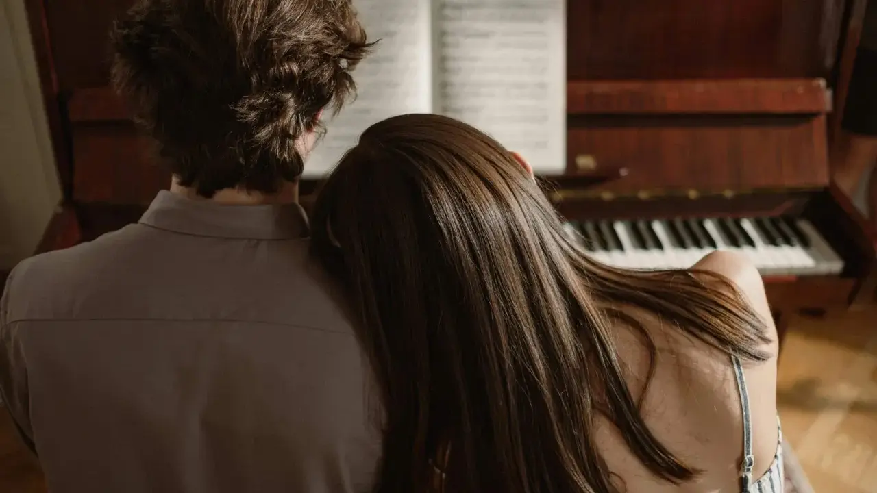 Pareja compartiendo un momento íntimo junto a un piano, el verdadero **exclusividad significado** de la conexión.