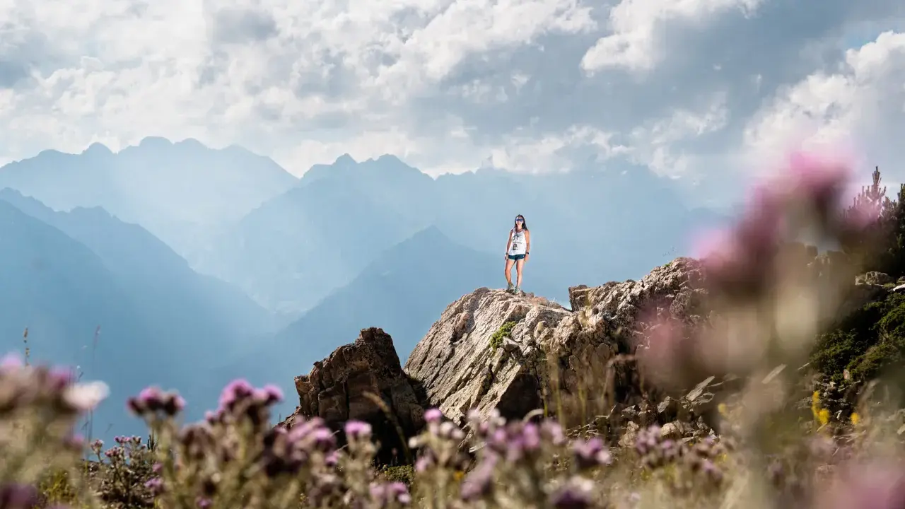 Una mujer en la cima de una montaña rocosa, disfrutando de las vistas. ¡Una gran idea de qué hacer en Cerler en verano!