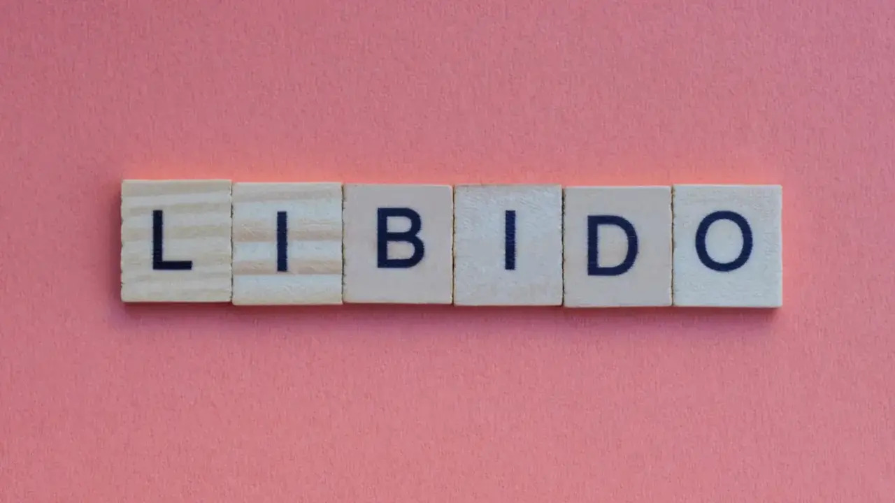 Słowa "LIBIDO" ułożone z klocków na różowym tle. Temat: spadek libido u mężczyzn po 30.