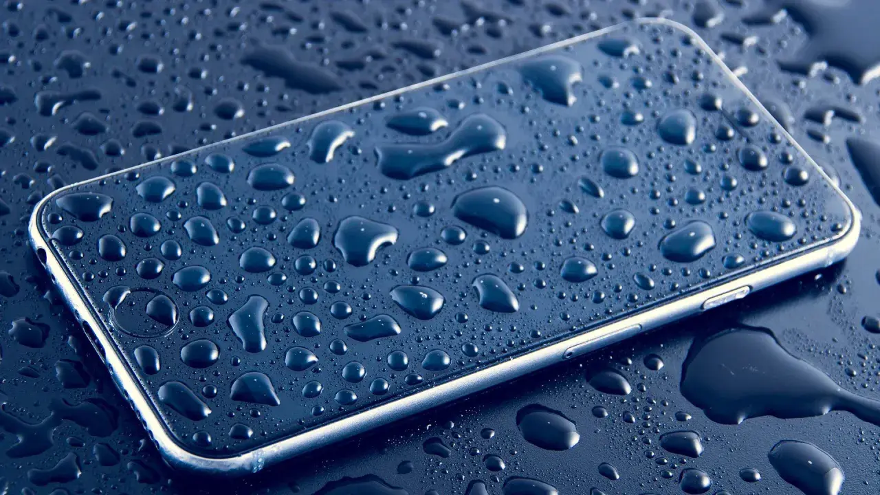 Smartfon pokryty kroplami wody, podkreślający jego wodoodporność IP.